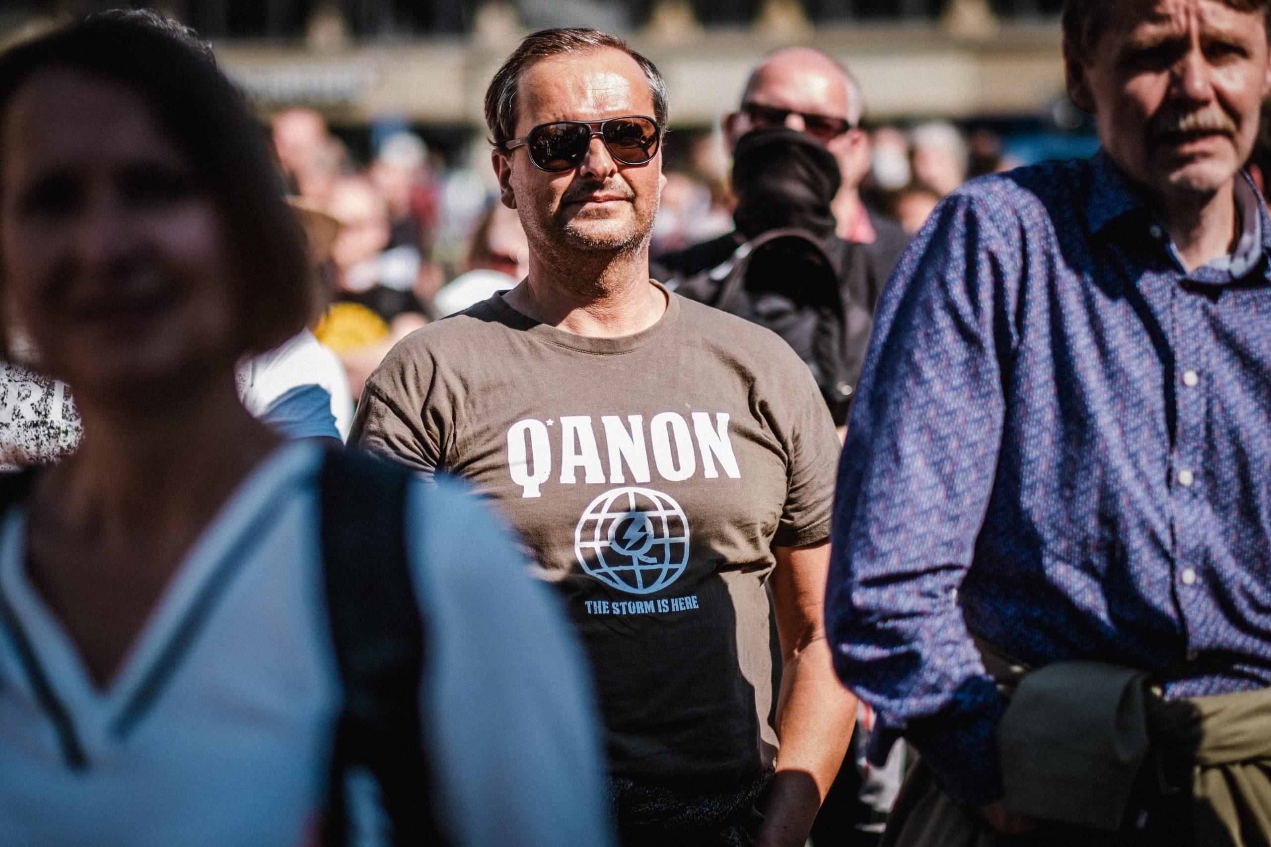 Ein Teilnehmer eines Corona-Leugner*innen-Protests mit QAnon-Symbolik